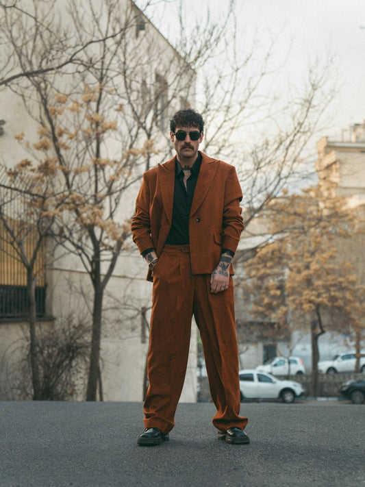 A man stands in a brown suit.